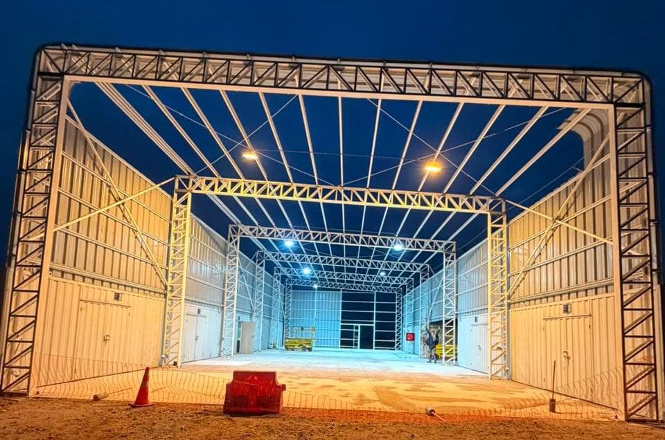 Galpón industrial con estructura metálica, iluminado de noche