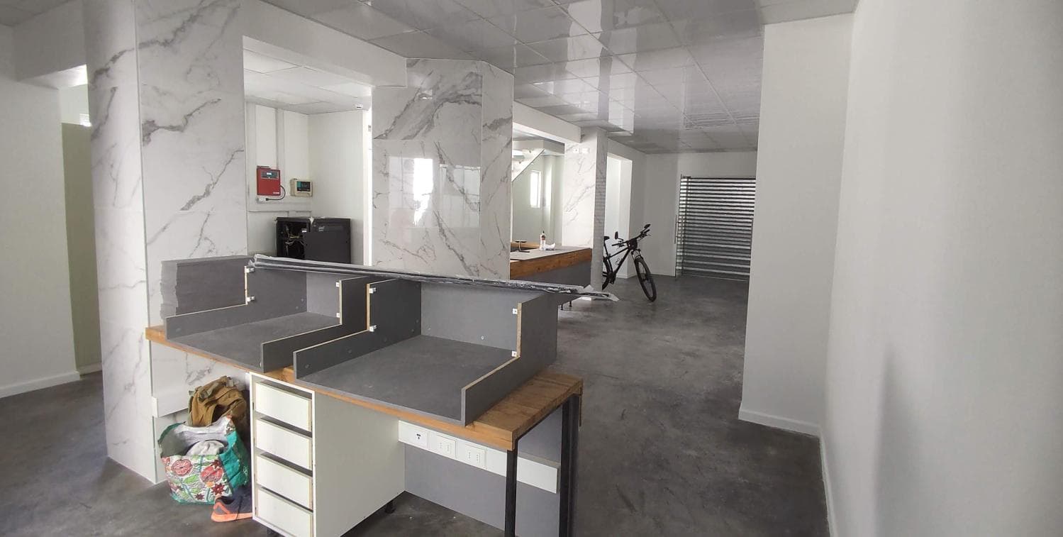 Oficina en obra, con mesones a medio armar y piso de cemento