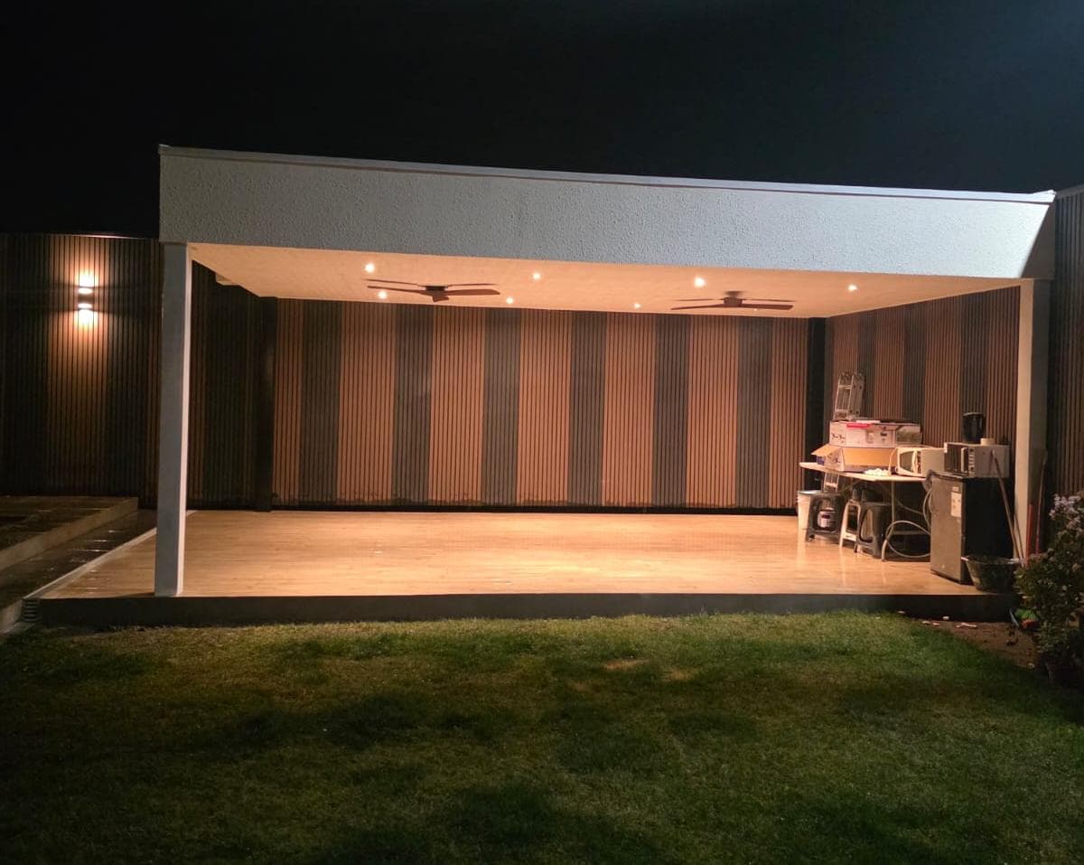 Quincho techado con deck de madera e iluminación cálida